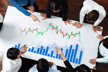 A dynamic scene of diverse professionals analyzing financial data on a large poster, emphasizing teamwork and strategic thinking in a modern office setting. Scalp