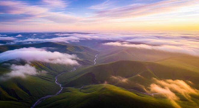 Aerial view of rolling green hills with a river, clouds, and a sunrise sky. The landscape is illuminated by golden light.