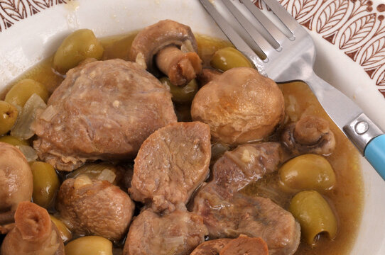 Assiette de viande de veau aux olives et champignons avec une fourchette en gros plan