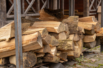 Wood is stacked in a storage area close to a building, ready for use in fireplaces or grills when the temperature drops