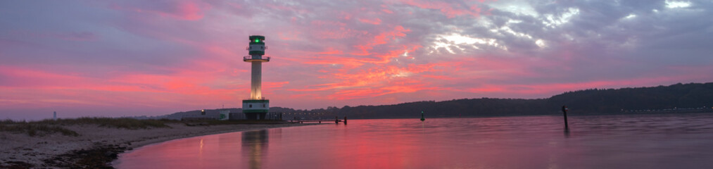 Falckensteiner Strand mit Leuchtturm und angestrahlten roten Wolken.