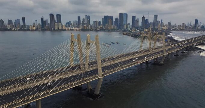 Cinematic aerial view of the Bandra Worli Sea Link in Mumbai, Maharashtra, India, during the monsoon season, with dramatic clouds and top shots of moving cars, captured from above the clouds.