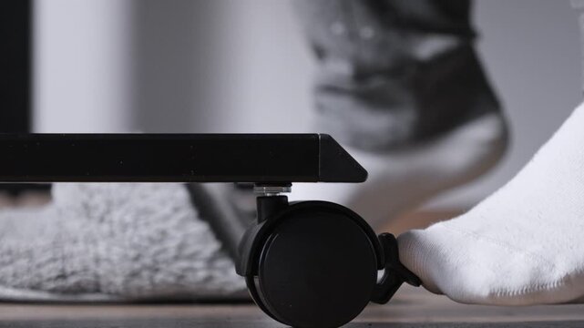 A person's foot in soft white socks gently pushes a black furniture caster wheel, showcasing effortless mobility and versatile arrangement for contemporary home interiors