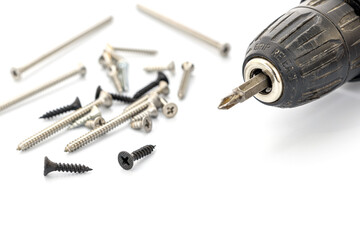Close-up of a Black Cordless Drill Next to Assorted Screws on White Background