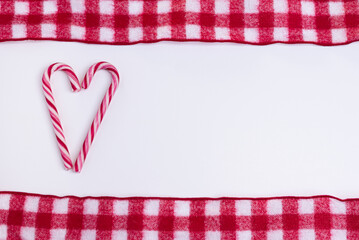 Obraz premium Christmas Candy Cane love heart with checkered ribbon above and below on white background with copy space