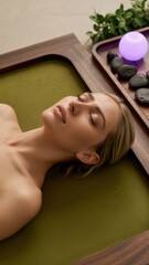 A serene scene featuring a woman relaxing on a green surface, surrounded by stones and a glowing orb, creating a tranquil atmosphere.