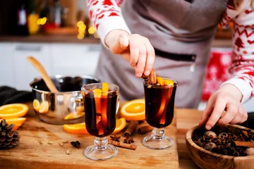 Fotobehang Muziek Woman garnishing hot mulled wine with cinnamon and star anise in christmas and new year kitchen creating warm aromatic holiday beverage with citrus and spicy winter notes  © 5ph