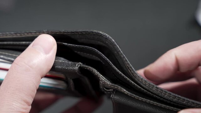 Close-up hands open a wallet and reveal it empty. Concept video for poverty, debt, budgeting, recession, or unexpected expenses.