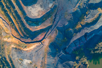 Abstract aerial view of massive S-curve contours of terraced earth with vibrant blue, orange, and...