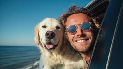 A man with sunglasses leans out of a car window with a joyful expression while his golden retriever dog happily rests beside him. They are near the ocean on a clear day.