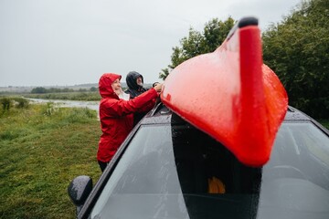 Senior couple loading kayak onto car in rain