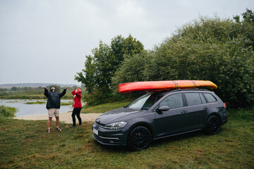 Couple catching raindrops at lakeside campsite