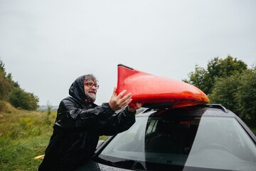 Man preparing kayak in rain for outdoor adventure