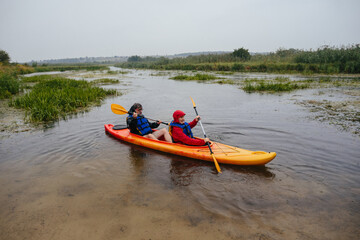 Senior couple kayaking river, embracing adventure in rain