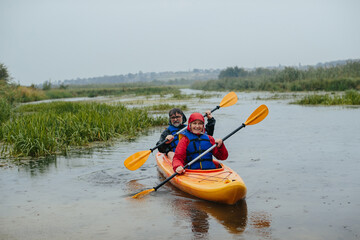 Senior couple kayaking together on river during rain
