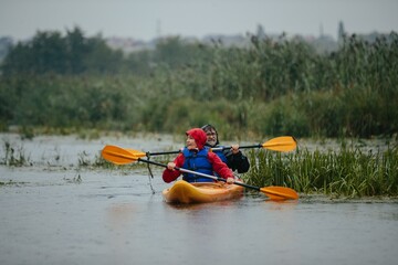 Senior couple kayaking together on river during rain