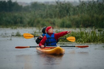 Senior couple kayaking in rain navigating nature