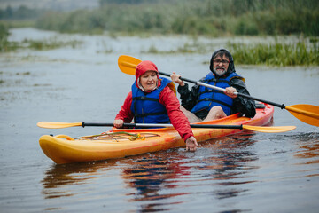 Senior couple kayaking on a lake in rain