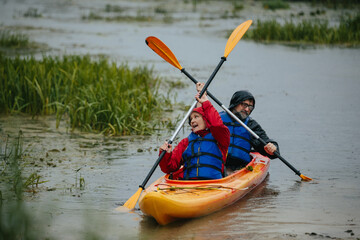 Senior couple kayaking in rain, embracing active lifestyle