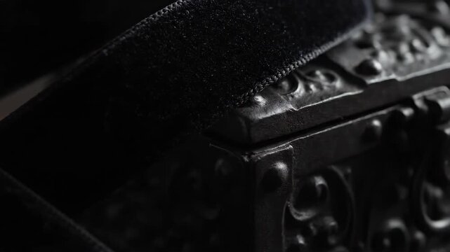 Close-up of a black velvet ribbon on an ornate, dark surface.