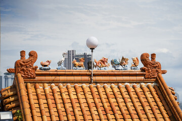A ornate, multi-tiered Chinese temple with vibrant red and green roofs, detailed eaves, colorful patterns and dragons,  set against a bright blue sky with scattered clouds