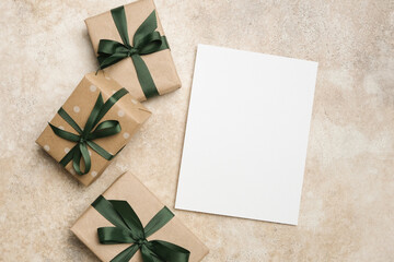 Greeting card mockup with blank space for design, surrounded by beautifully wrapped gift boxes over beige background, creating a festive and inviting atmosphere for celebrations