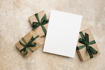 Greeting card mockup with blank space surrounded by beautifully wrapped gift boxes featuring green ribbons, perfect for holiday celebrations and special occasions