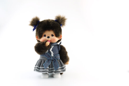 a popular classic doll toy , Monchichi or Monchhichi , Japanese cute monkey fur doll display on white table with white wall background in souvenir tourist shop in Japan