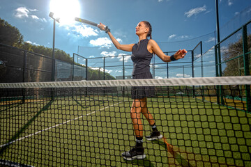 Woman Padel tennis player with racket in action on the court. Girl athlete with paddle racket on court outdoors. Sport concept.