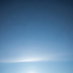 A serene night sky with a gentle glow illuminating the distant horizon and scattered stars above