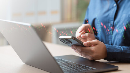 A person analyzing stock market charts on a smartphone while working at a laptop, focusing on digital trading insights. Finance concept. Stock market trader chart. Finance lifestyle concept.