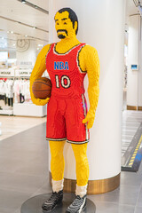 Obraz premium Life-sized Lego sculpture of a red basketball player number 10 in a neutral background, posed actively with one arm on hip and holding a basketball - Kyiv, Ukraine - November 12, 2025