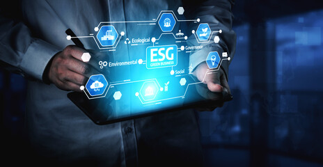 A professional man interacts with a tablet showcasing ESG icons, symbolizing critical concepts in sustainability, innovation, and governance within a modern office environment. Tessel