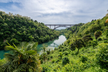 San Michele Bridge spans the Adda River with its elegant iron arch, one of the world&rsquo;s tallest single-span iron bridges, standing proudly amid lush hills and reflective waters.