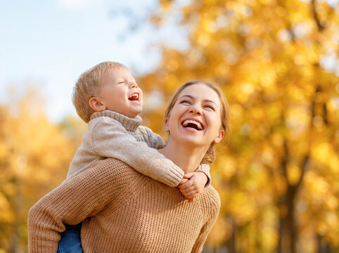 Mother carrying son piggyback park copy space autumn nature fall season family fun mom child playing outdoors leaves trees happiness parenting lifestyle walk love togetherness active joyful day - Powered by Adobe
