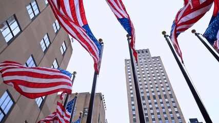 Wind waves American flags on the poles outdoors. Low angle view at the flags decorating the street of New York, USA. - Powered by Adobe