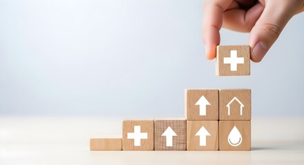 Hand stacking wooden blocks with medical cross, upward arrows, house and water drop icons for health and growth concept