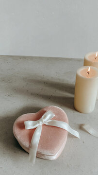A delicate Valentine gift. A soft pink heart presents. Gentle lighting and candles enhances the romantic mood, capturing emotion and heartfelt sentiment