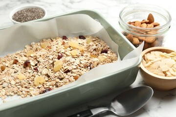 Making granola. Oat flakes, dried fruits, almond nuts and honey on white marble table, closeup