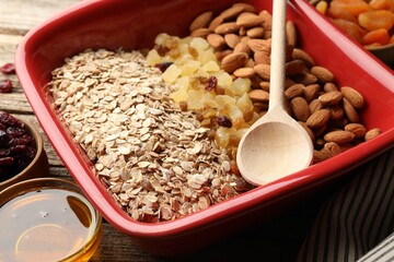 Making granola. Oat flakes, dried fruits, almond nuts and honey on wooden table, closeup