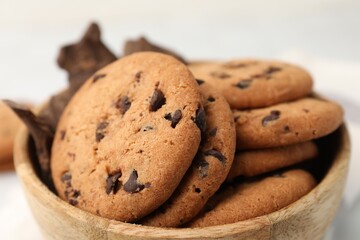 Yummy chocolate chip cookies and pieces of chocolate in bowl on table, closeup