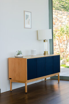 Navy blue ribbed sideboard standing in living area holding glass terrarium, smart speaker, lamp