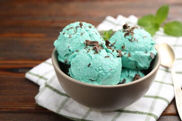 Tasty mint chocolate chip ice cream, spoon and towel on wooden table, closeup