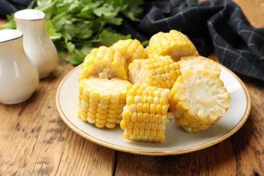 Pieces of boiled corn cobs on wooden table, closeup - Powered by Adobe