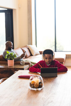 African American father and son using smartphone and tablet while sitting in living room