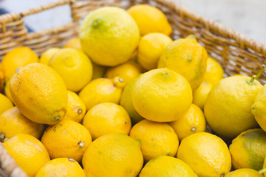 Lemons resting in woven wicker basket sitting on wooden countertop under soft natural lighting