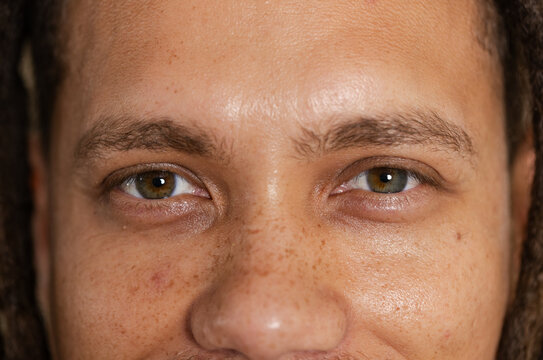 Adult male gazing straight ahead in studio, showing skin texture freckles and brown-green eyes