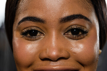 African American woman posing in studio, showing jewel under right eye, gold stud earring