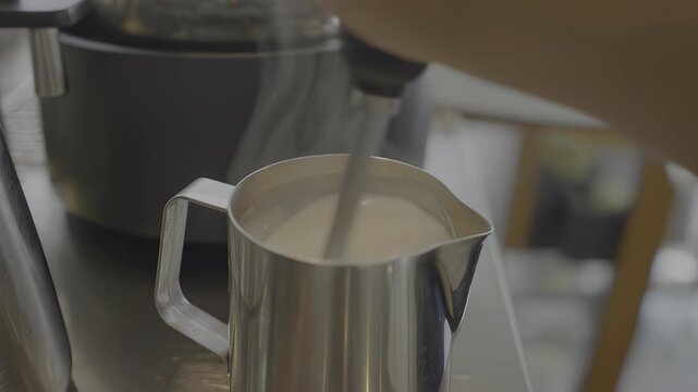 Steaming milk being poured into a pitcher