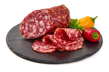 Salami with sliced pieces, garnished with red and yellow peppers, presented on a slate serving platter, isolated on white background